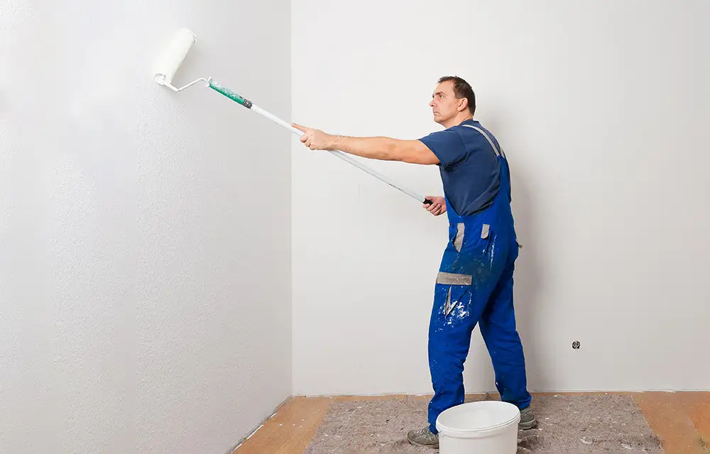 Ein Mann streicht eine Wand mit weißer Farbe